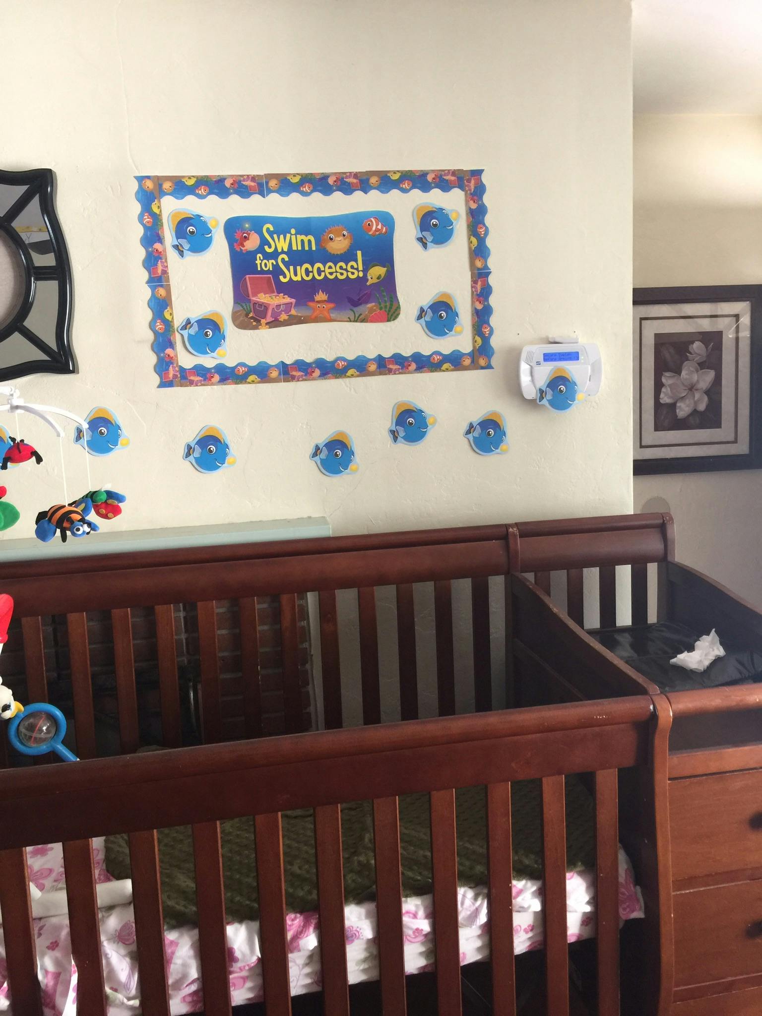 Crib and changing table with a "Swim for Success!" sign on the wall