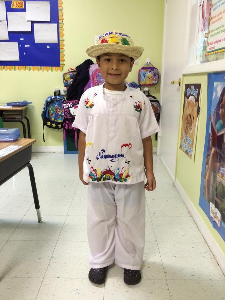 Child in a classroom wearing a white outfit and a straw hat