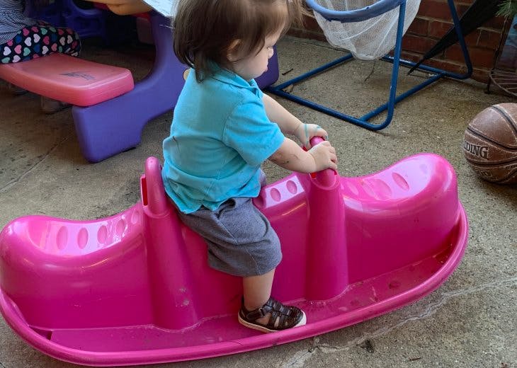 Child on a pink plastic seesaw
