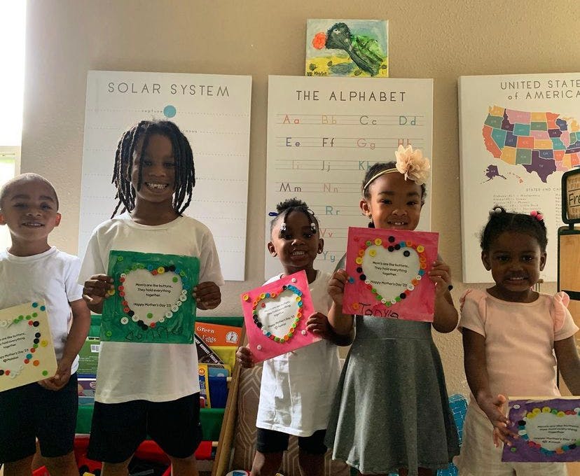 Five children holding up certificates in a classroom