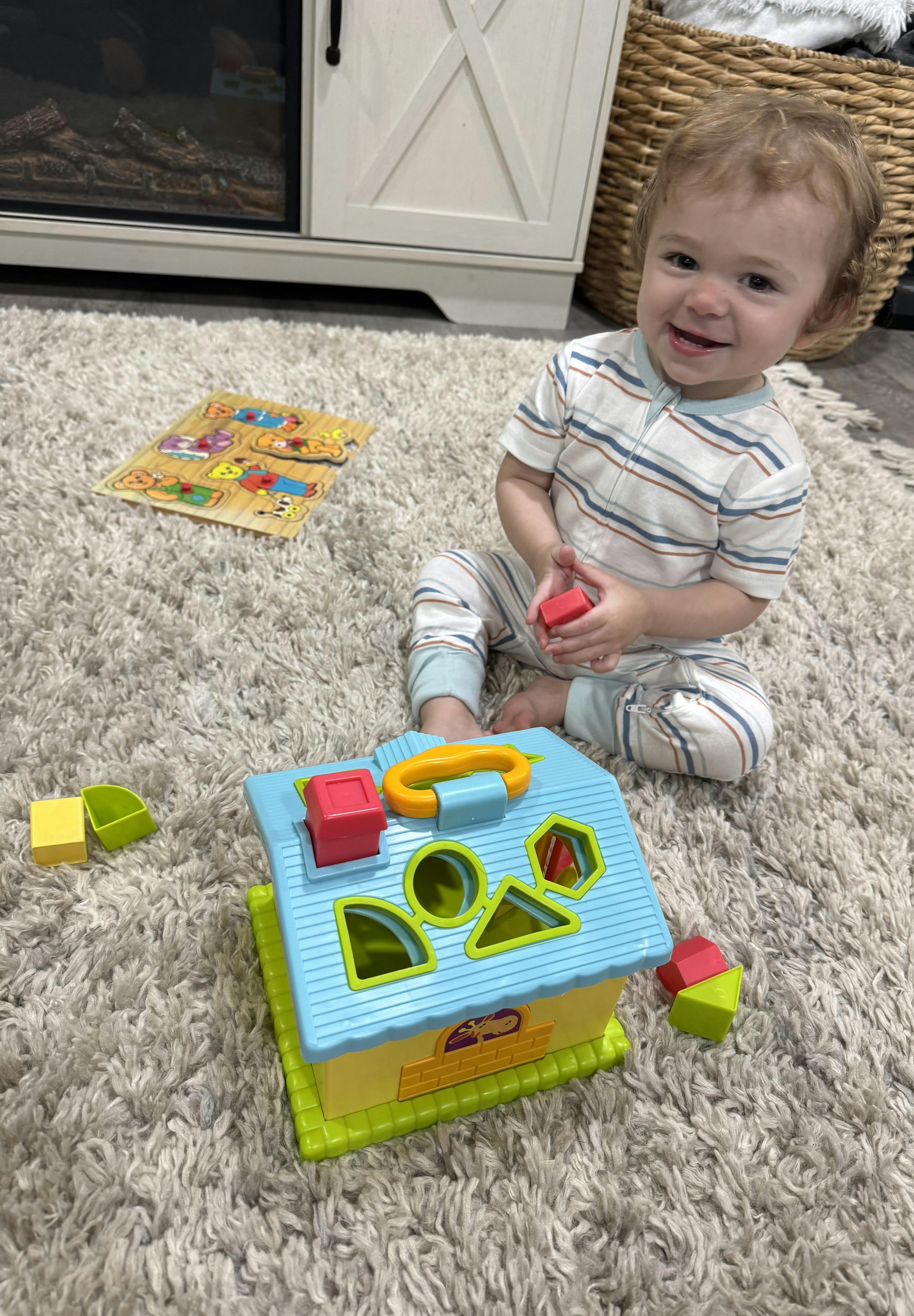 Child playing with a shape sorter toy on a rug