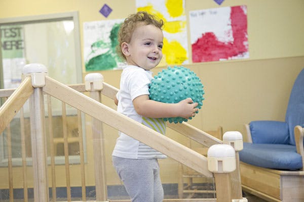 Child holding a textured ball in a play area