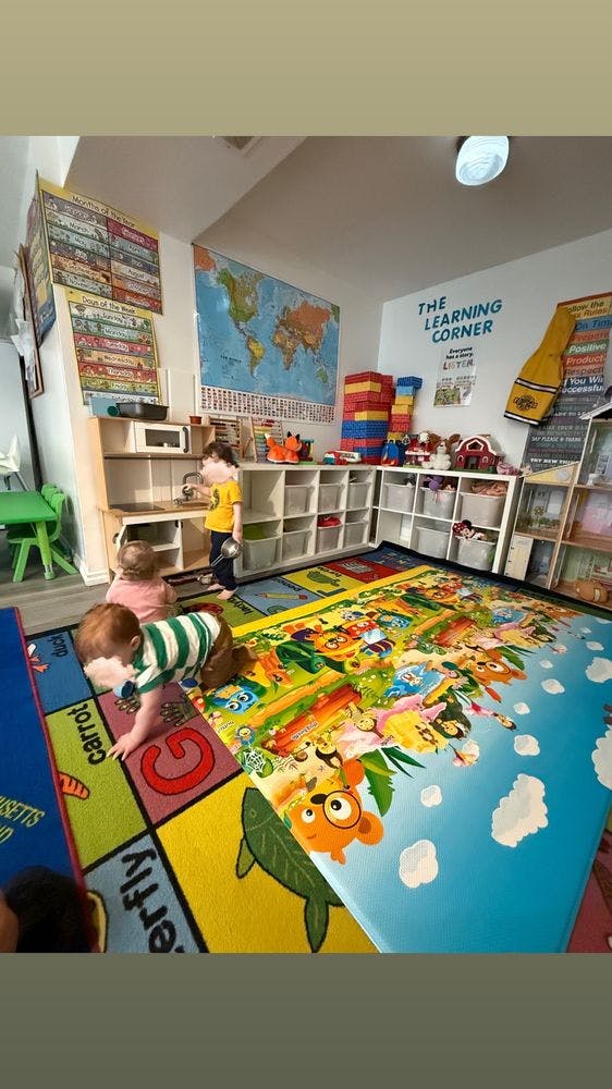 Three children playing on colorful rugs in a classroom