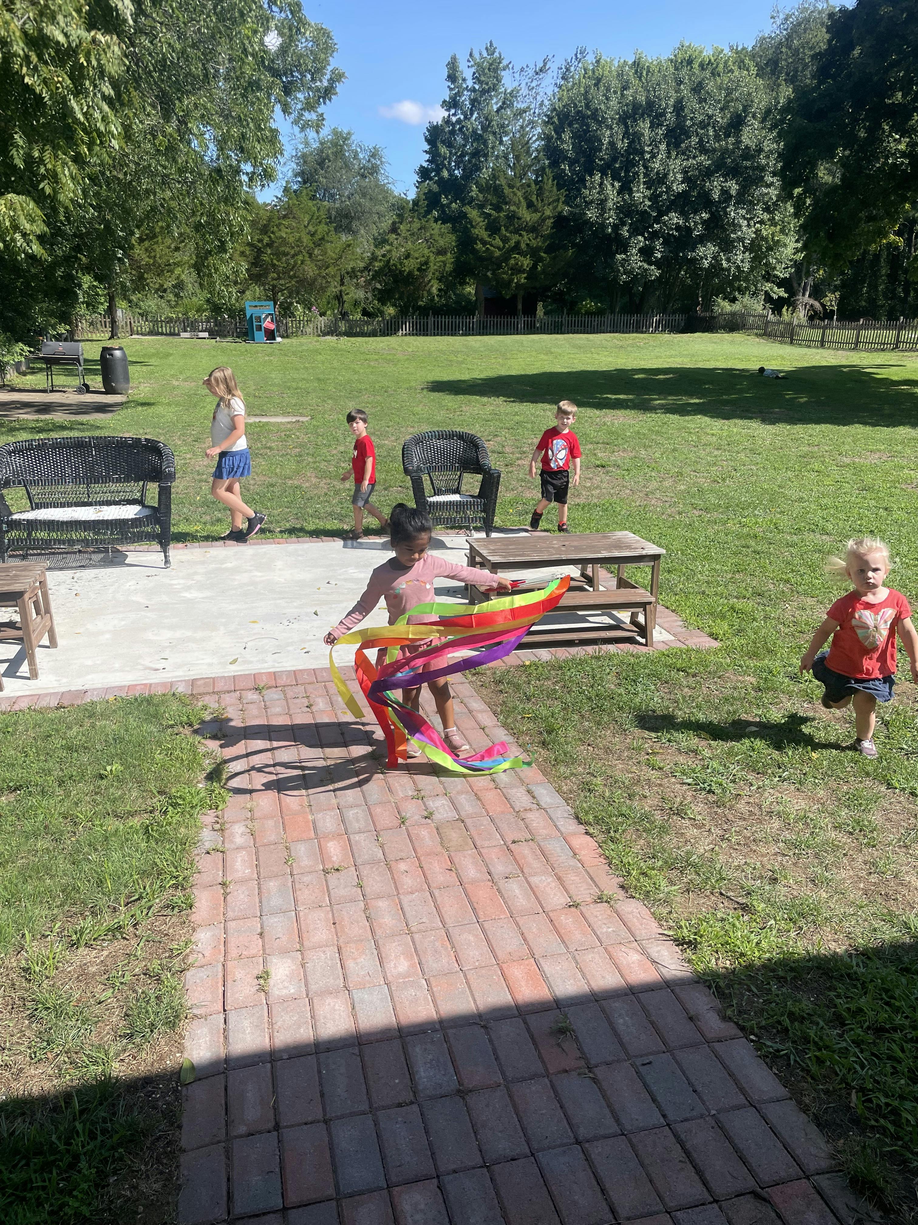 Children playing with colorful ribbons in a grassy backyard