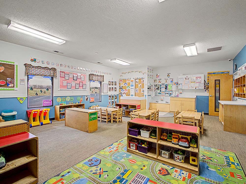 Empty colorful children's classroom with small tables, chairs, and play mats