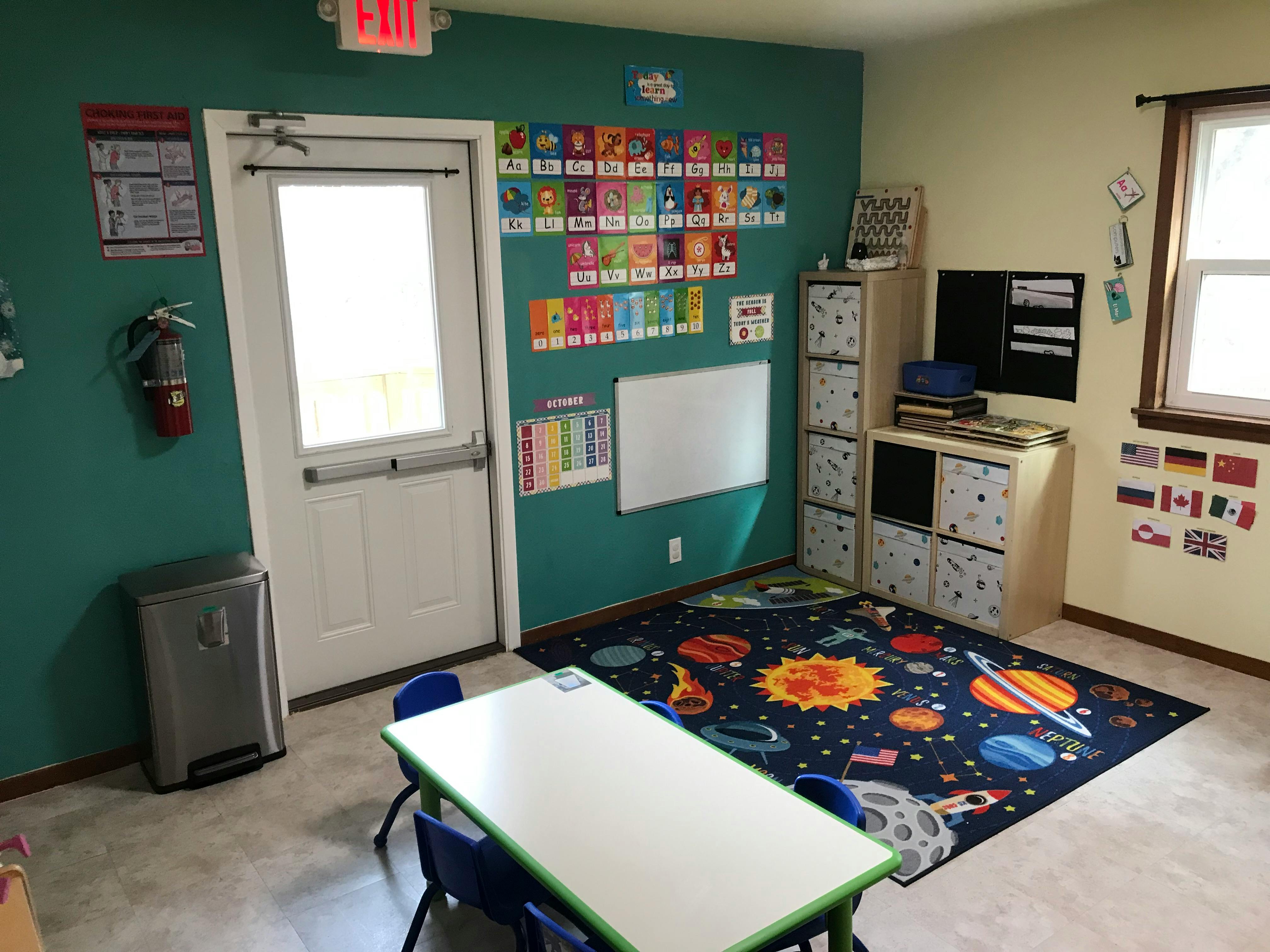 Classroom with a space-themed rug, small table, and chairs