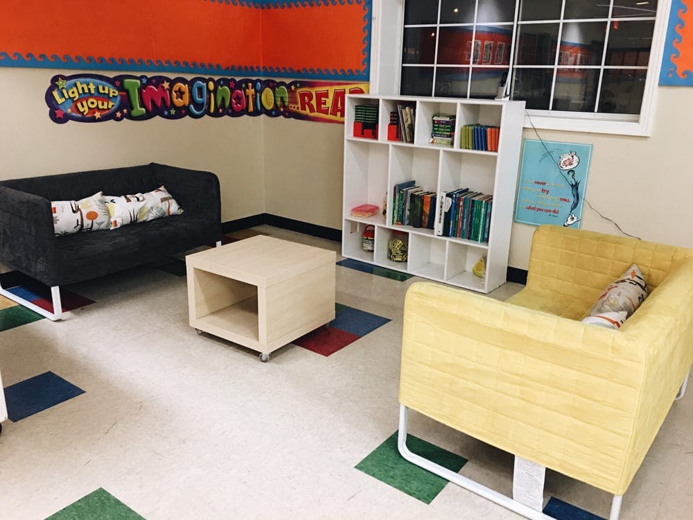 Reading nook with a couch, chair, and bookshelf in a classroom