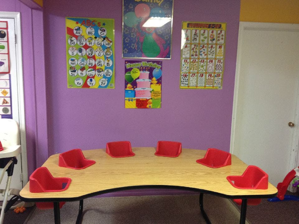 Classroom with a curved table and red chairs, posters on a purple wall
