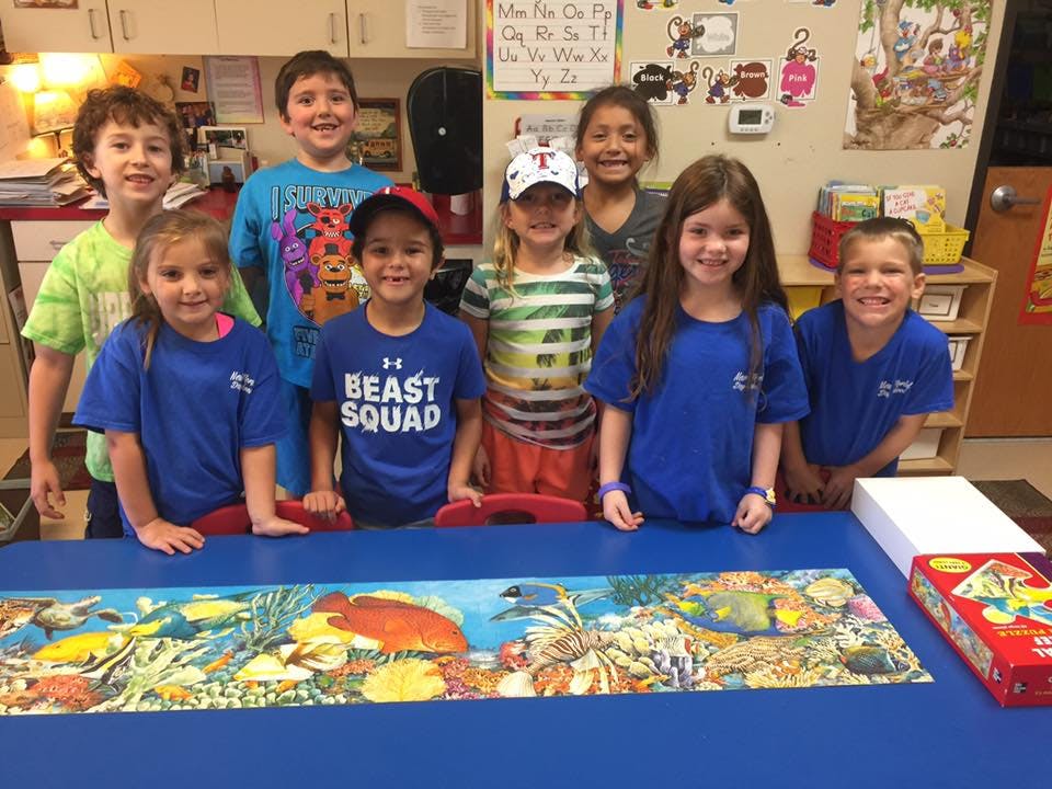 Group of children standing behind a table with a puzzle
