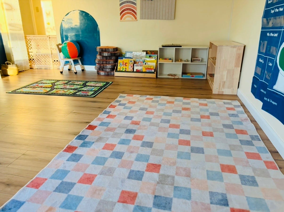 Playroom with multiple rugs, shelves, and a child's chair with a ball