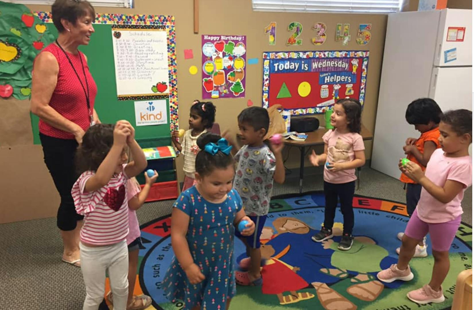 Adult and children playing with small balls in a classroom
