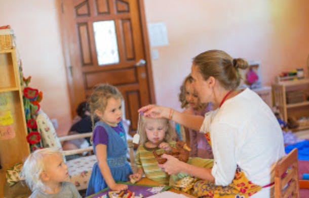 Person interacting with children in a classroom