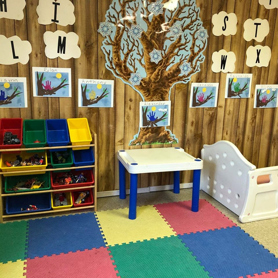 Classroom with toy storage, small table, and colorful floor mats