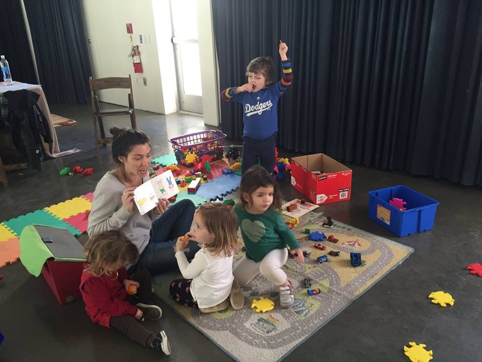 Person reading to children surrounded by toys