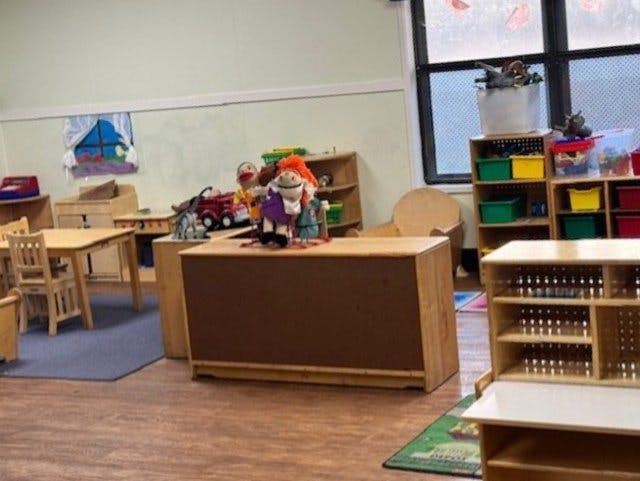 Classroom with wooden furniture, toys, and puppets