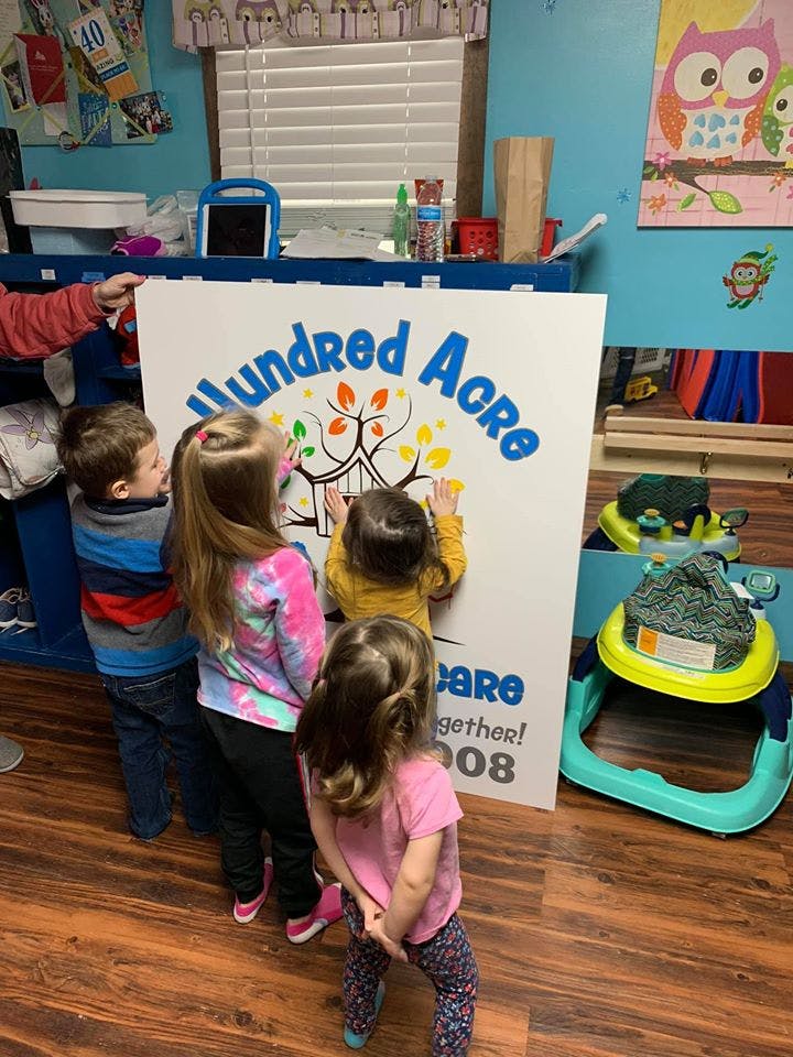 Children looking at a sign that says "Hundred Acre"