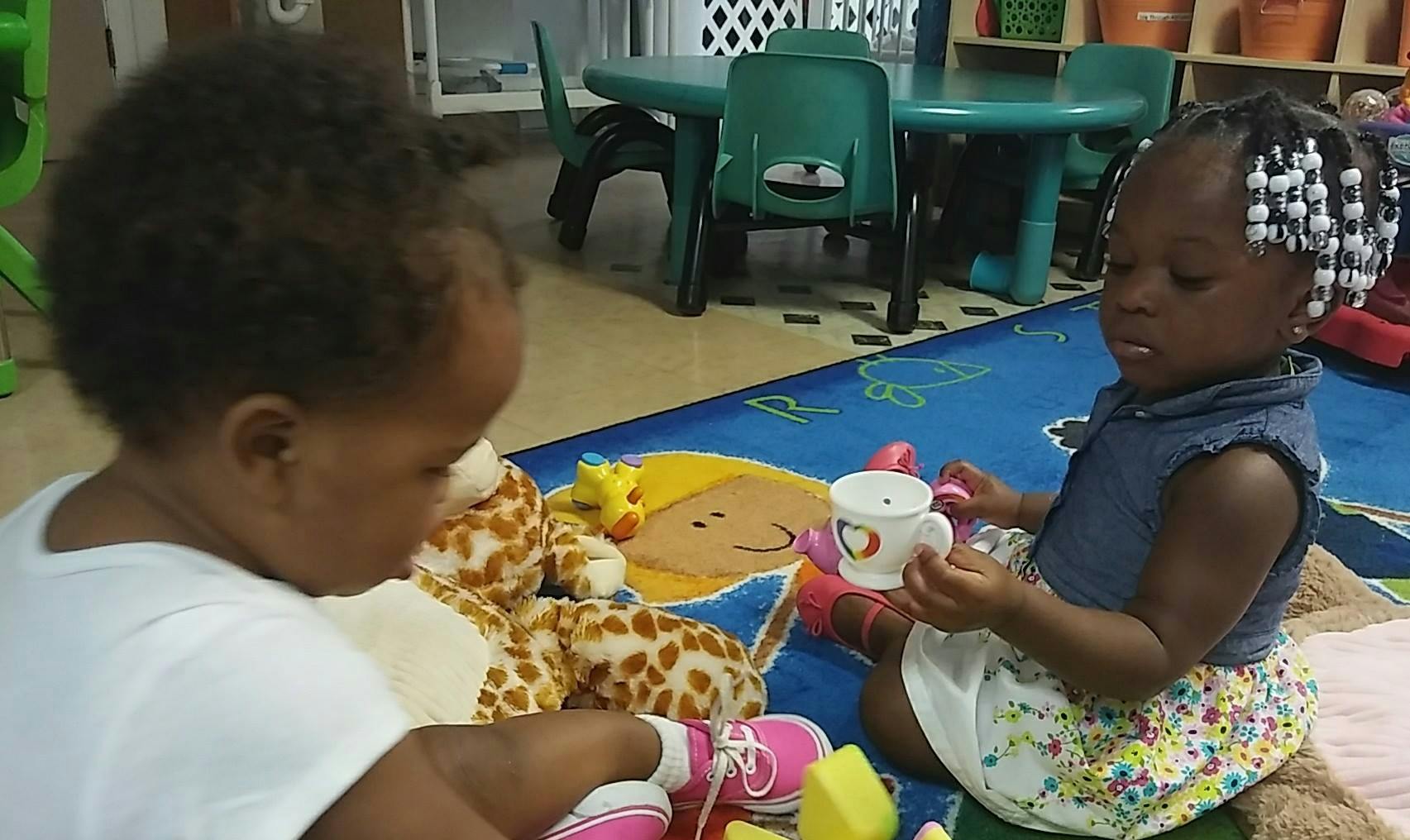 Two children playing on a rug with toys