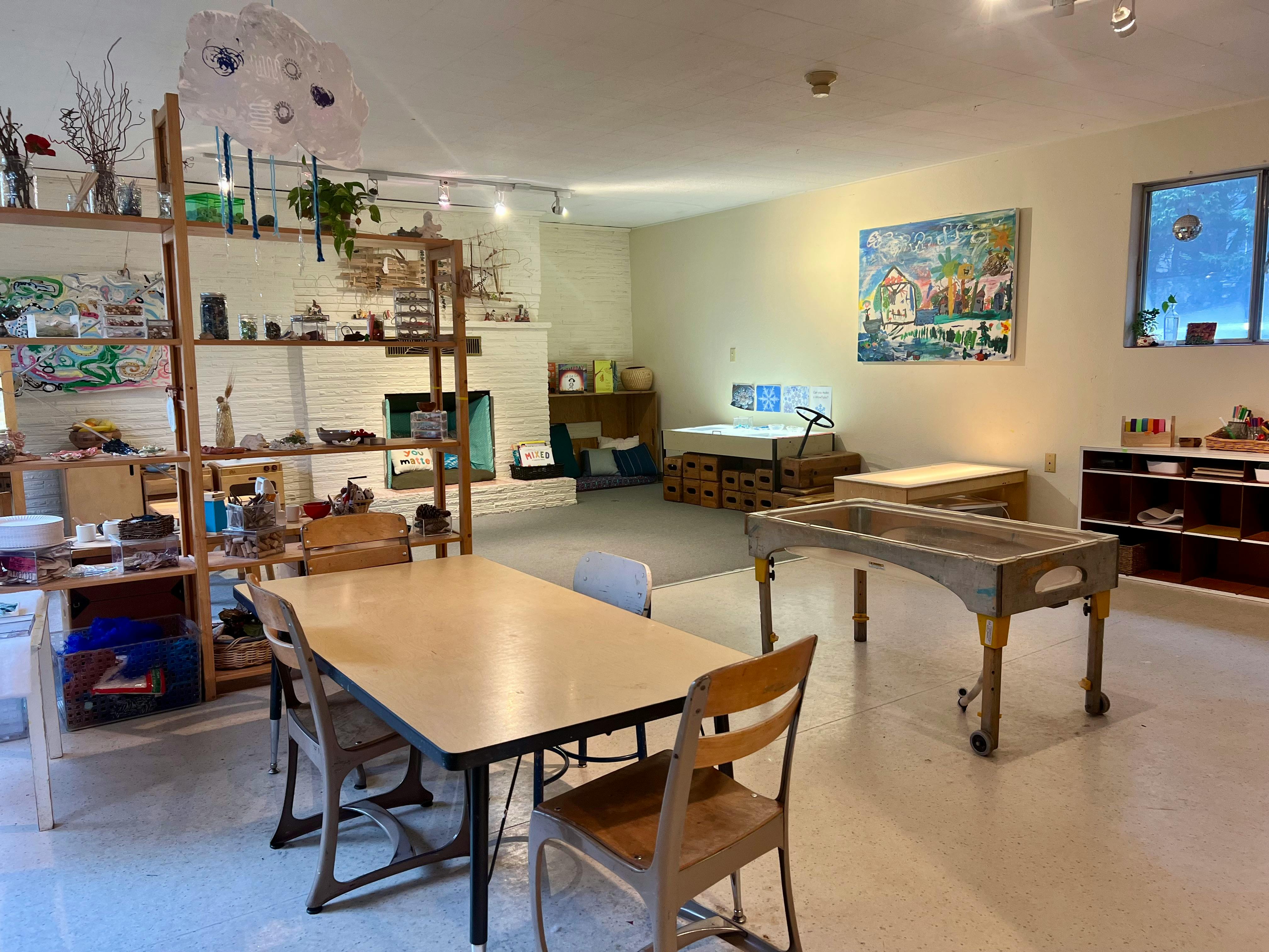 Classroom with tables, chairs, and shelves with various items