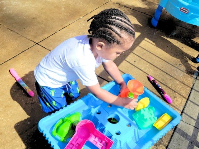 Child playing with toys on a water table outdoors