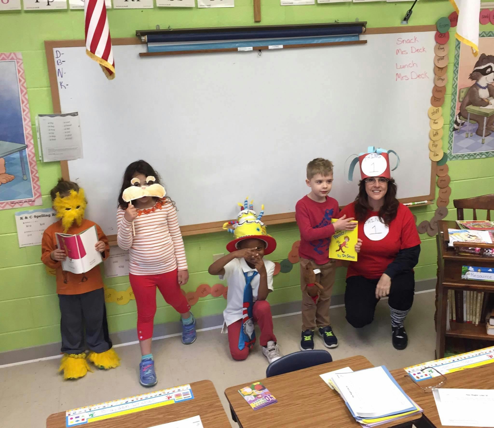 Adult and children in costumes holding books in a classroom