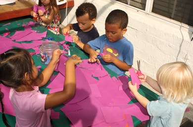 Children cutting purple paper with scissors