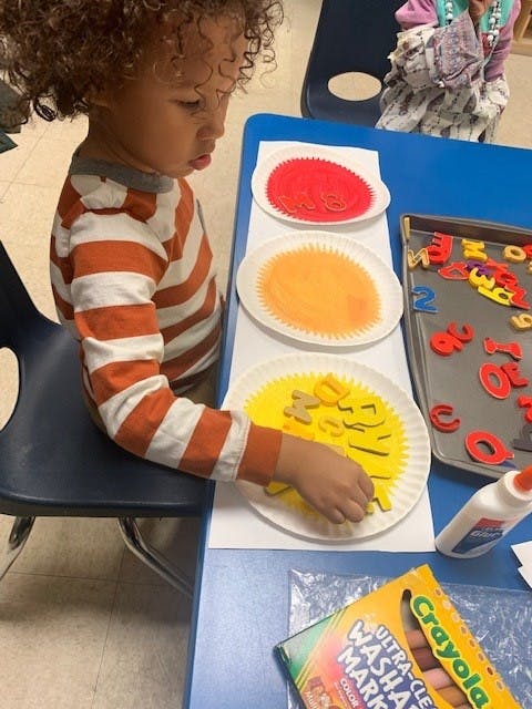 Child doing an art project with paper plates and letters