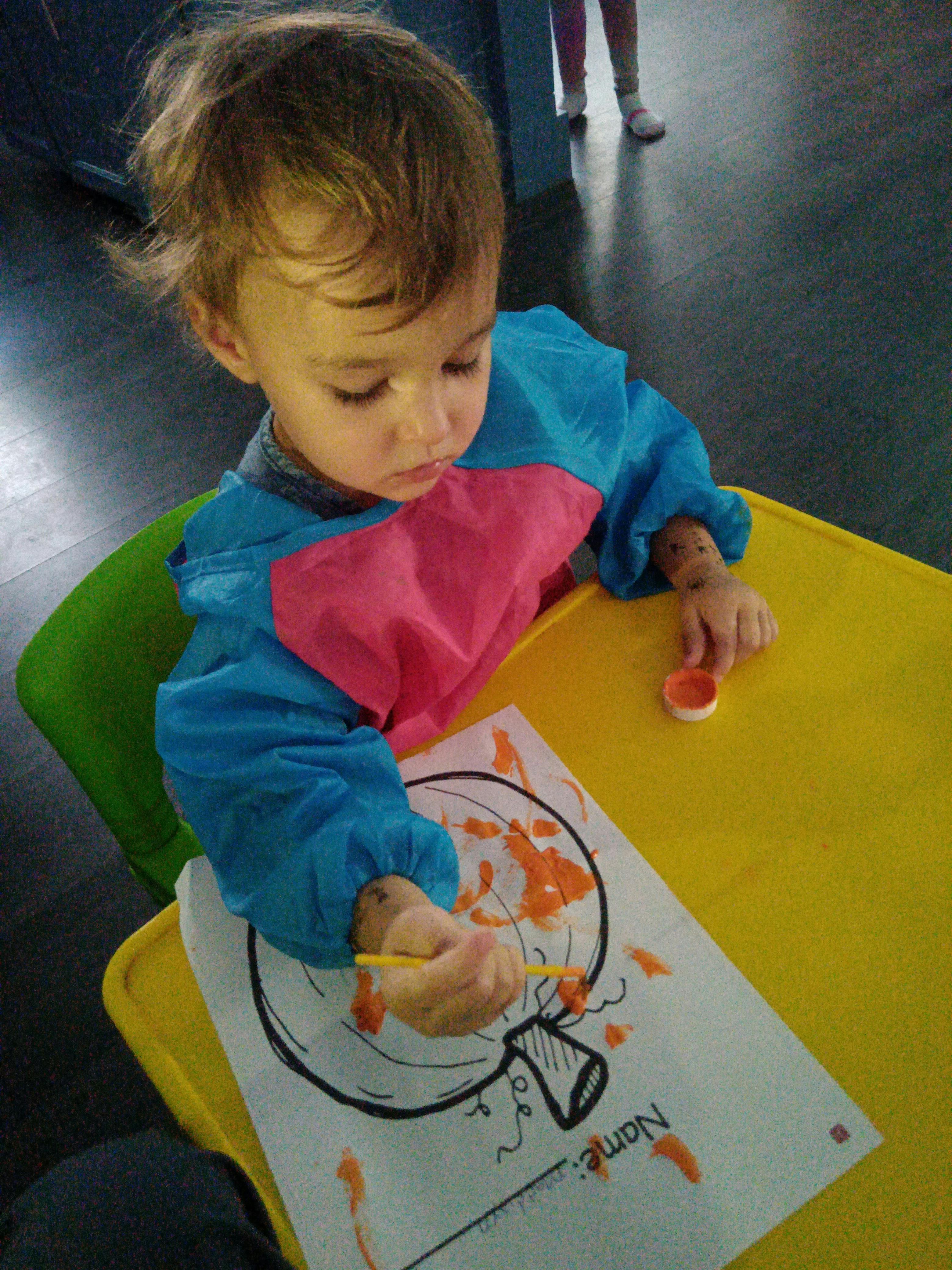 Child painting a pumpkin outline on paper