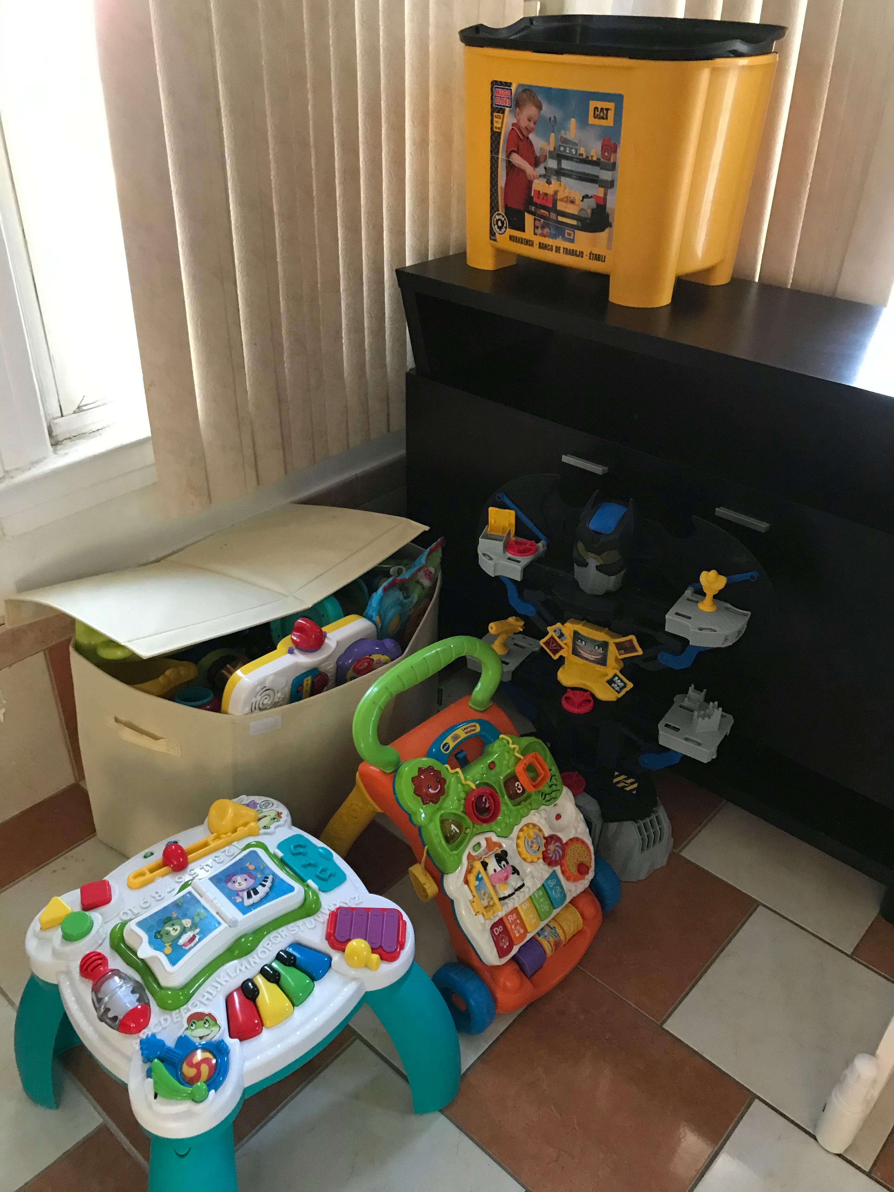 A toy storage bin, a baby walker, and an activity table