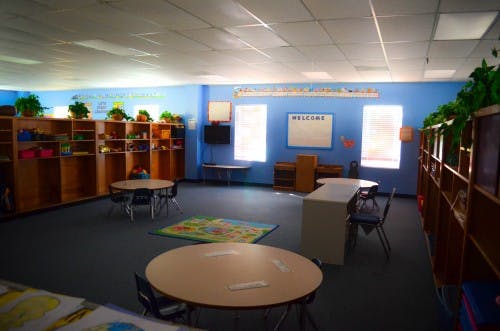 Empty classroom with blue walls, small tables, and shelves