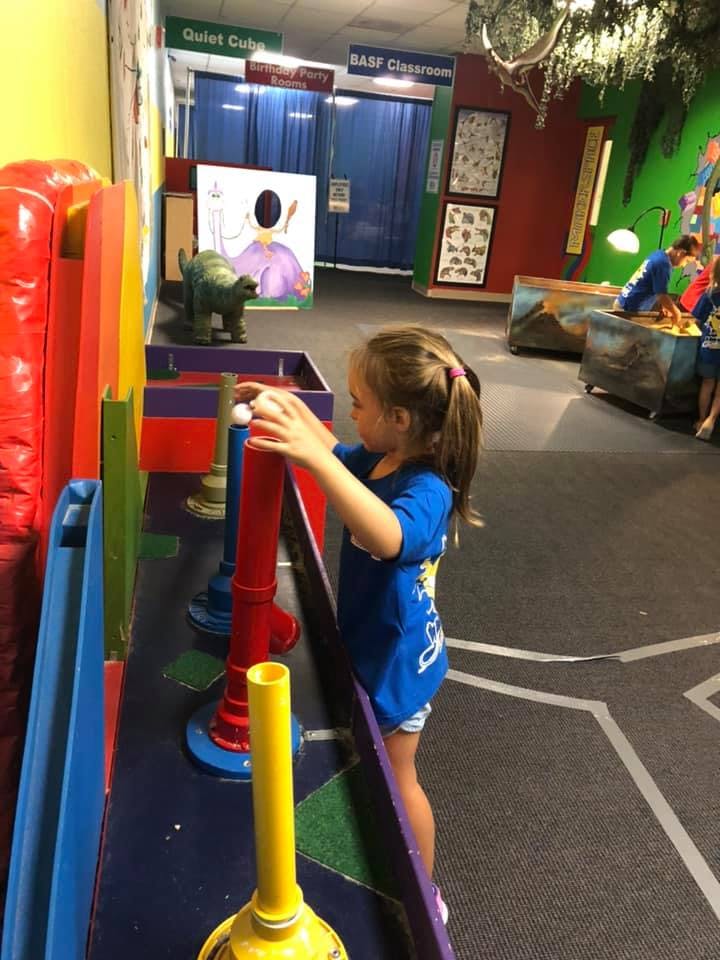 Child playing with a ball and colorful tubes