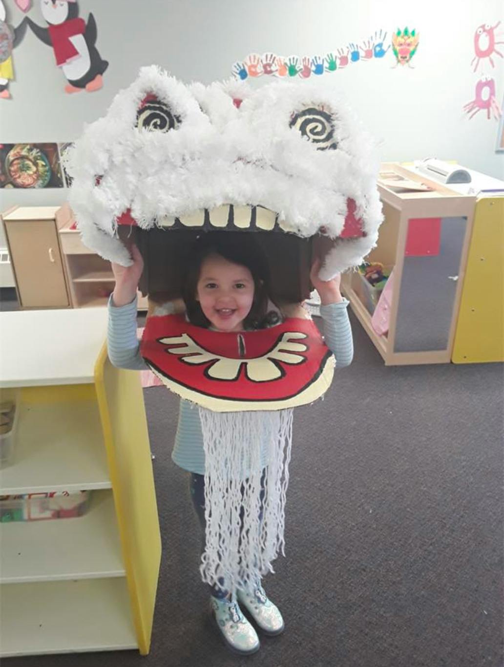 Child wearing a large white costume head with teeth and red trim