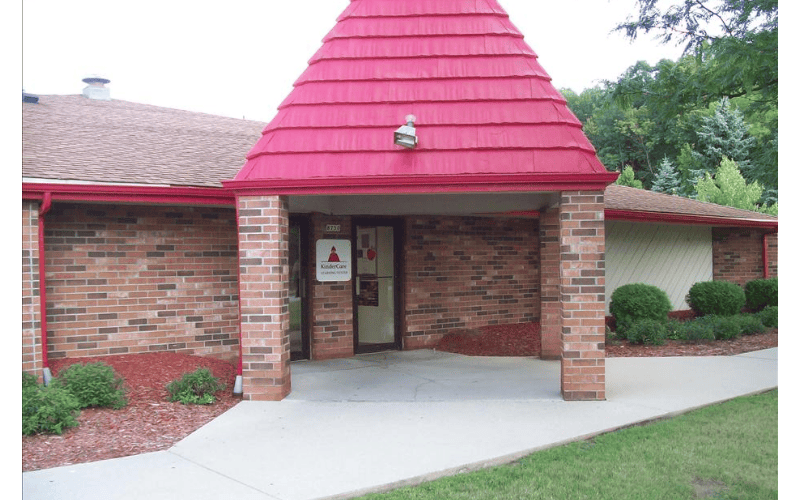 Brick building with a red pointed roof over the entrance and a KinderCare sign