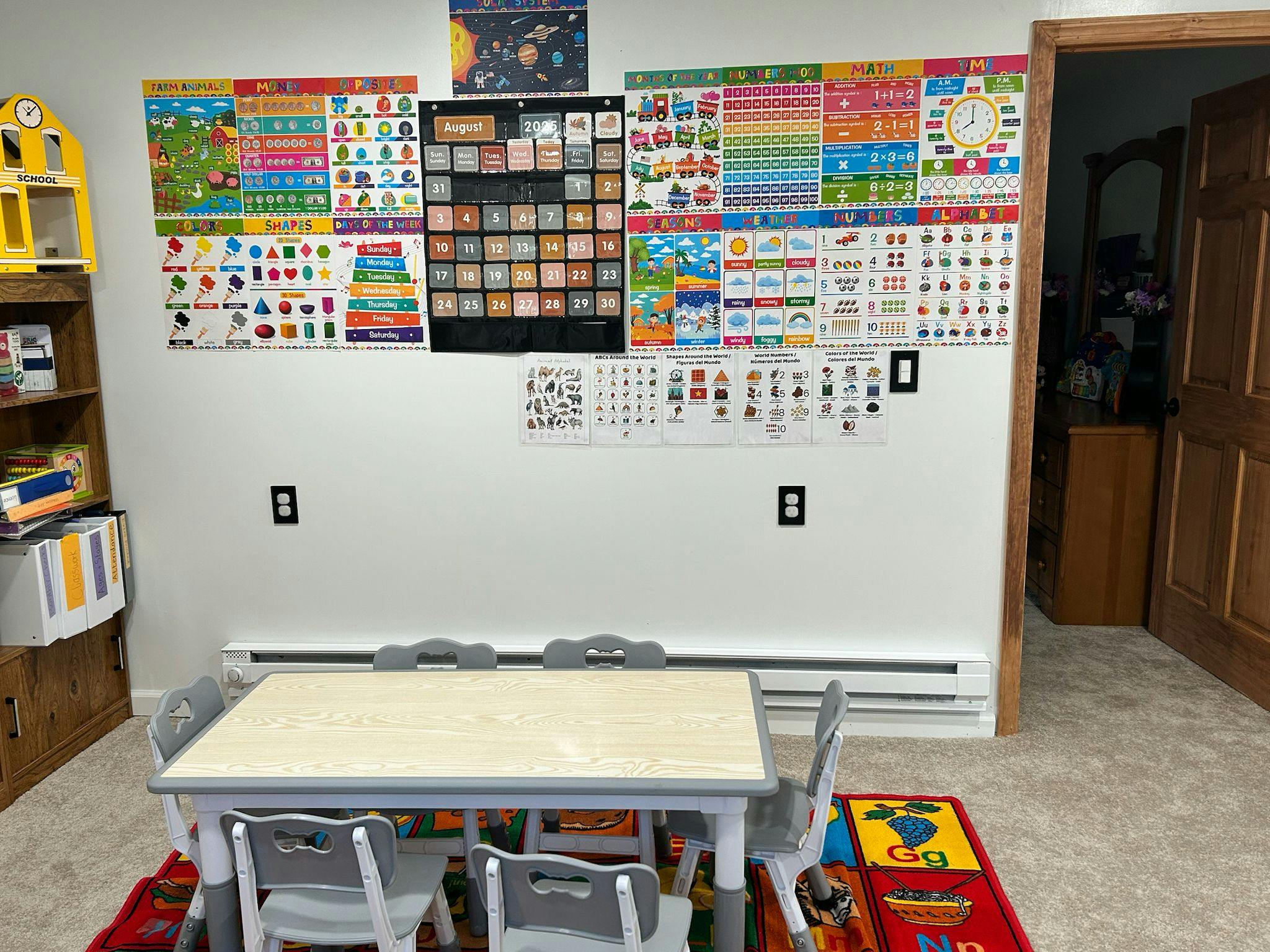 Small table with chairs in front of a wall decorated with educational posters