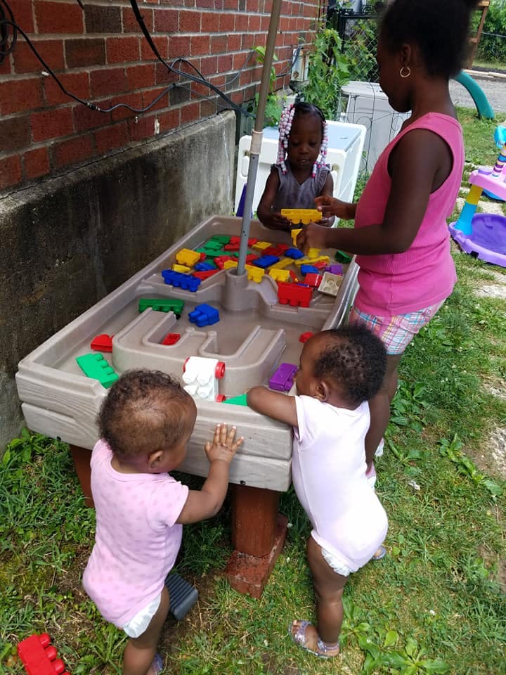 Three children playing with a water table outdoors
