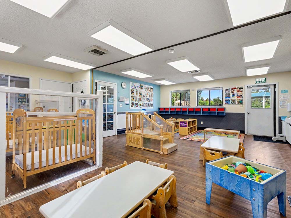 Cribs, small tables, and play equipment in a daycare room