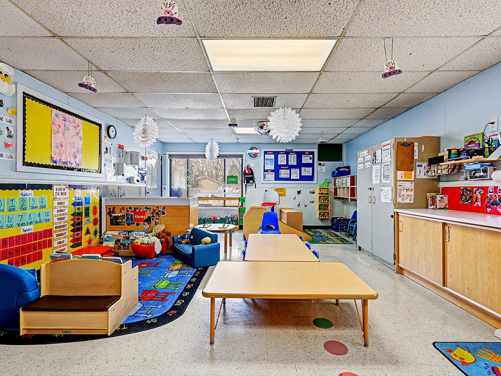 A colorful empty classroom with various learning stations and small tables