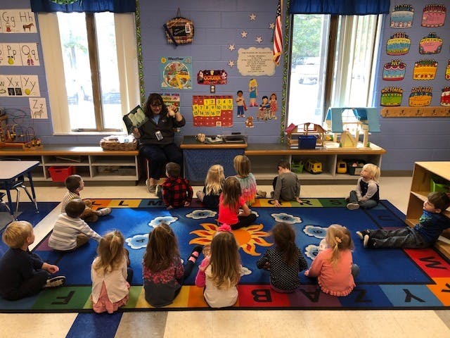 Adult reading to children sitting on a rug in a classroom