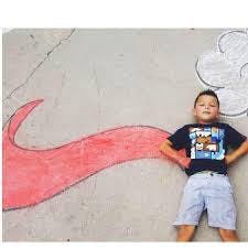 Child lying on ground next to a large red chalk drawing