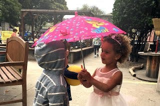 Two children under a pink umbrella
