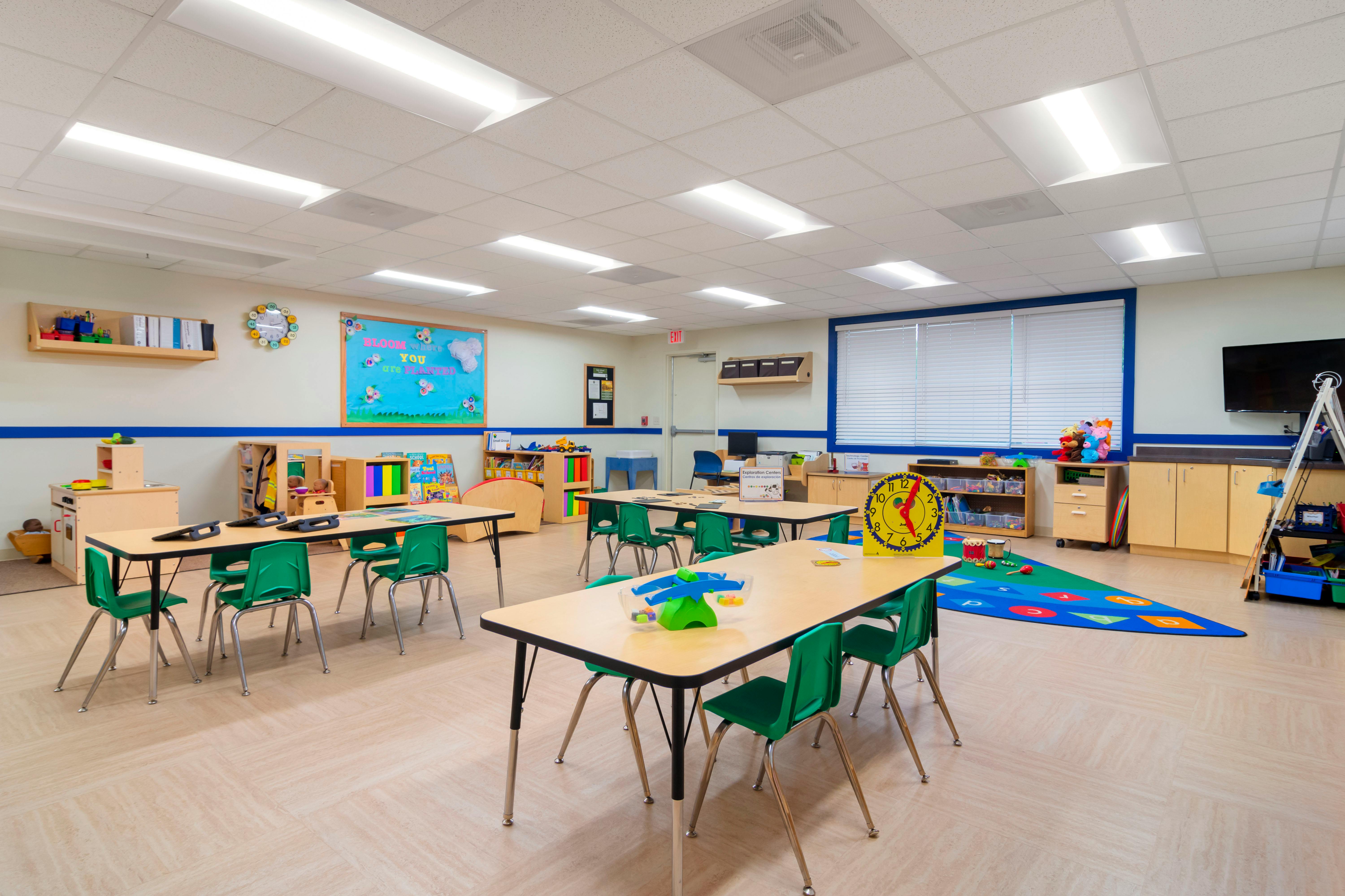 Empty classroom with small tables and green chairs