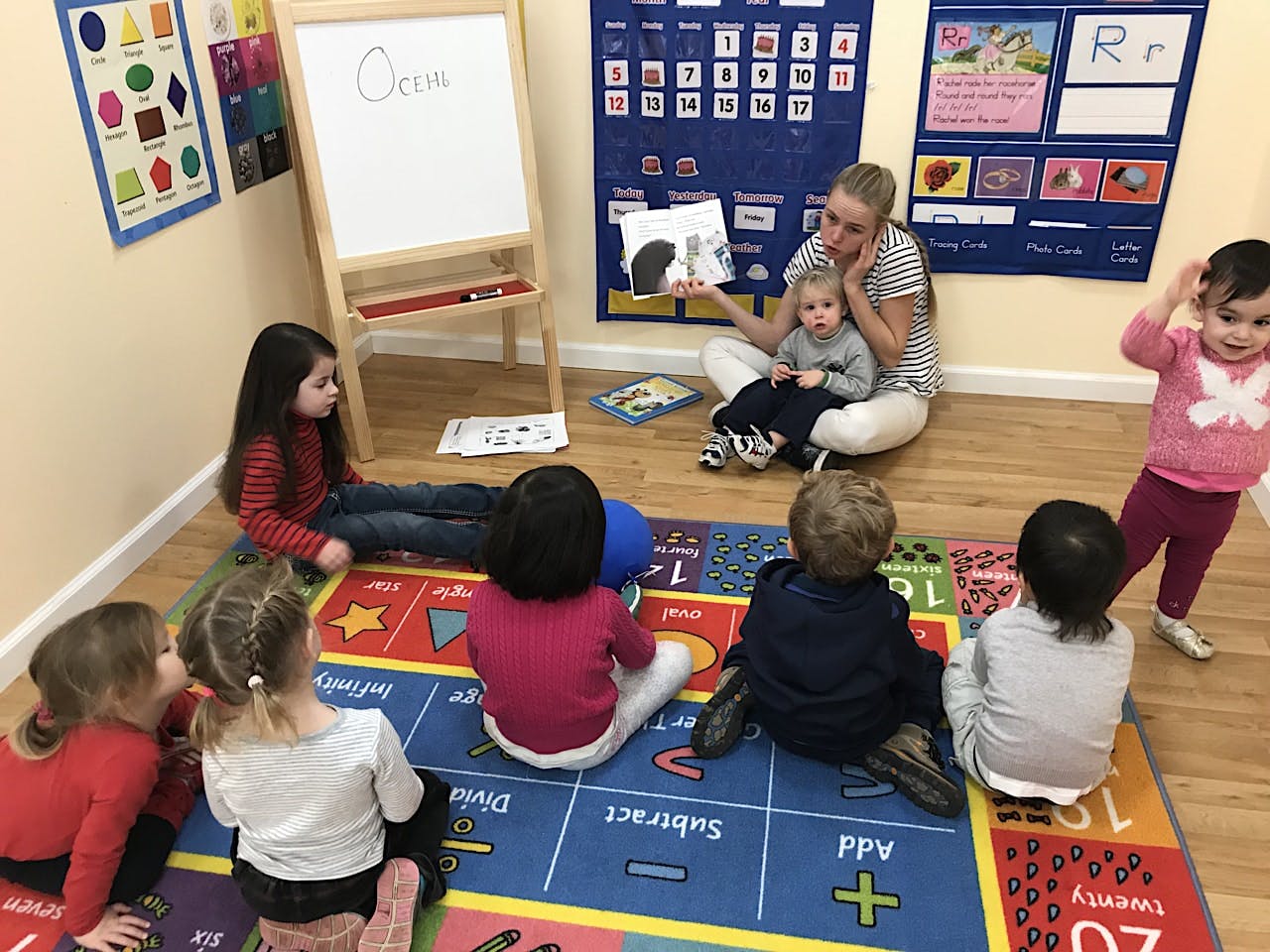 Adult reading a book to children sitting on a rug