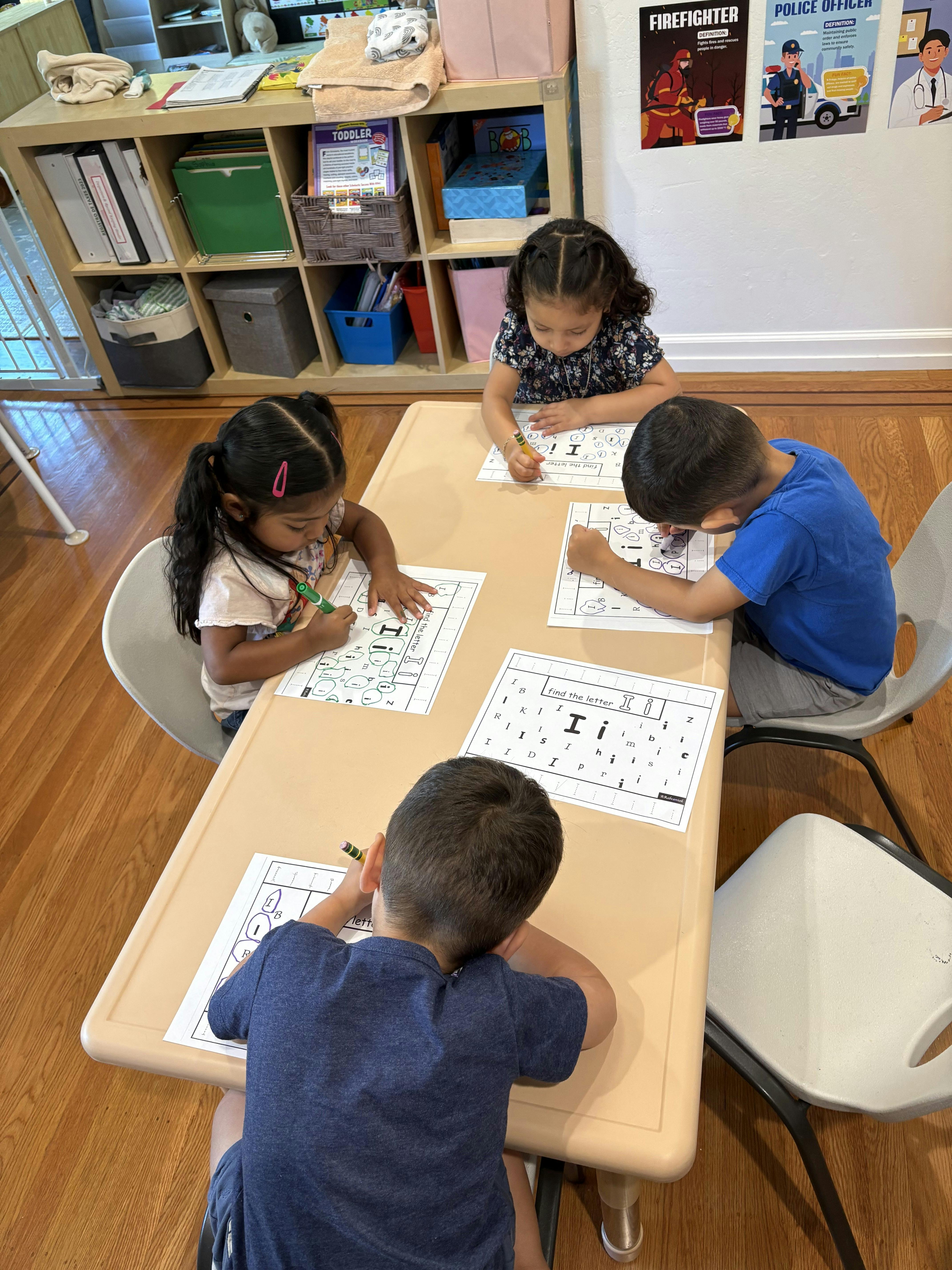 Four children coloring at a table in a classroom