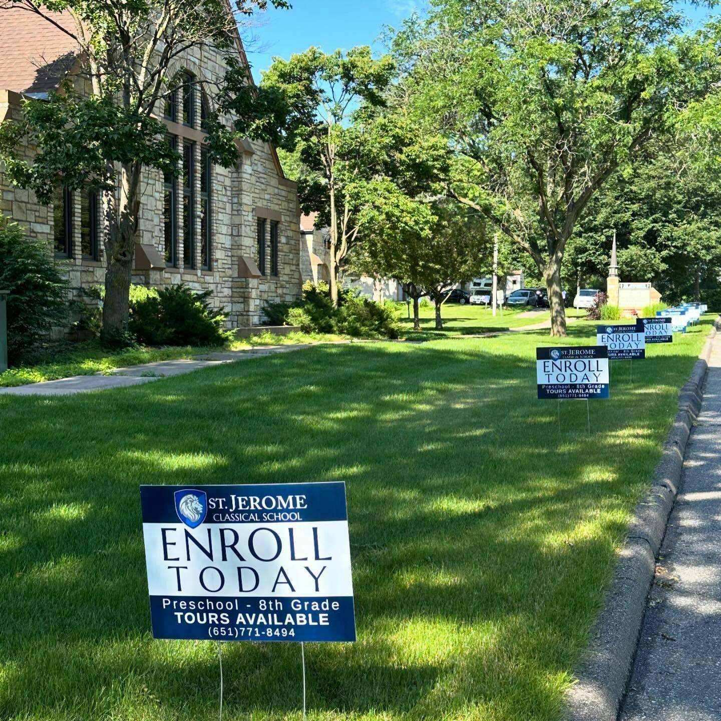 St. Jerome Classical School "Enroll Today" signs on a lawn outside a stone building