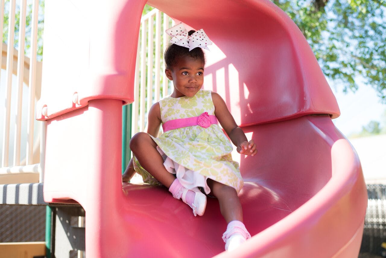 Child sitting on a pink slide