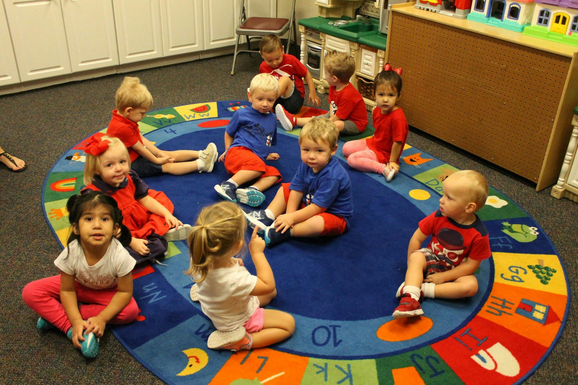 Children sitting on a colorful rug in a classroom