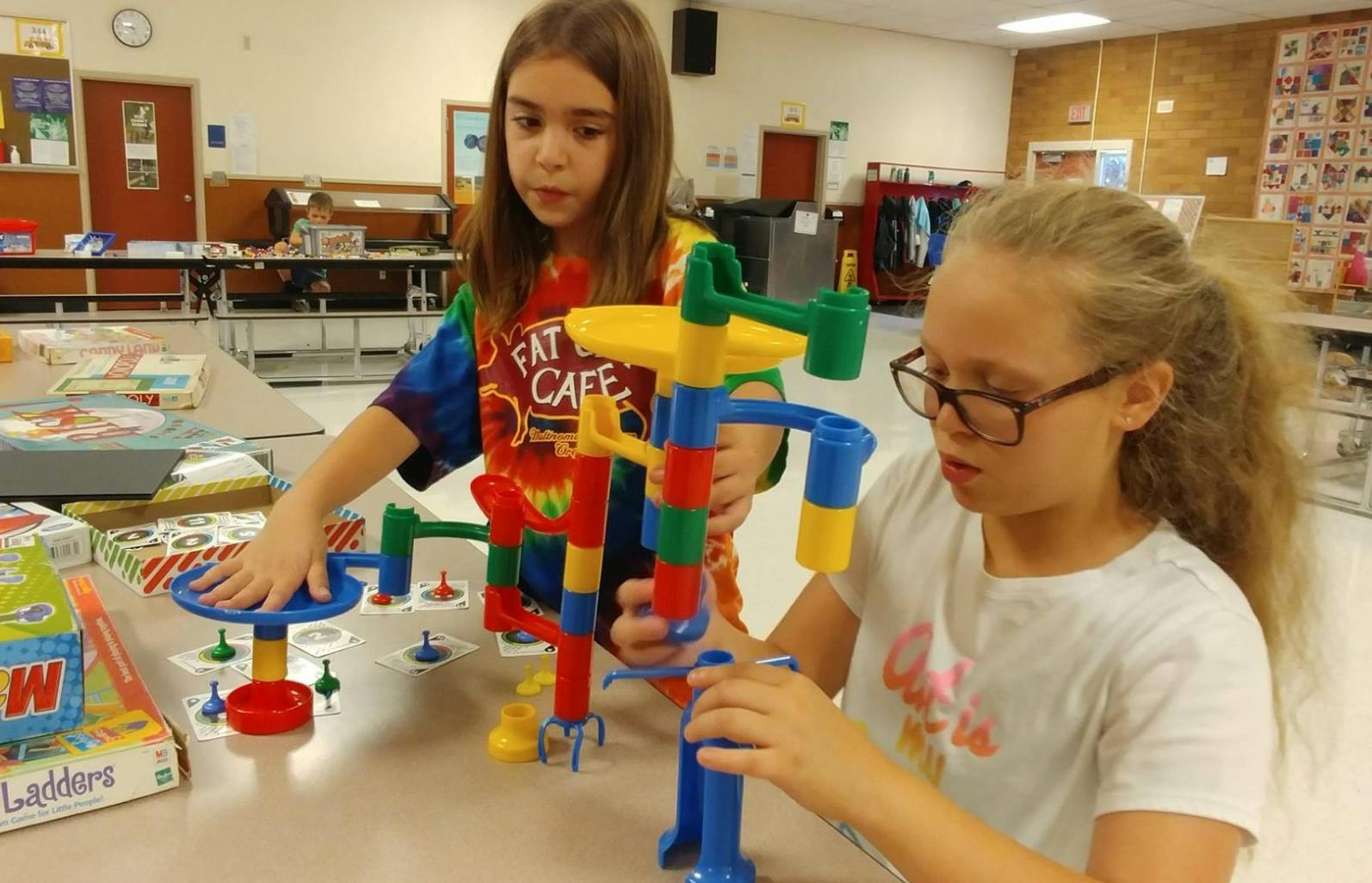 Two children playing with a colorful marble run toy in a classroom