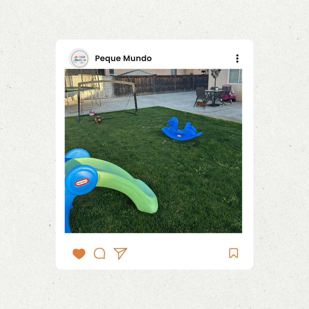 Playground equipment on a green lawn with a fence in the background