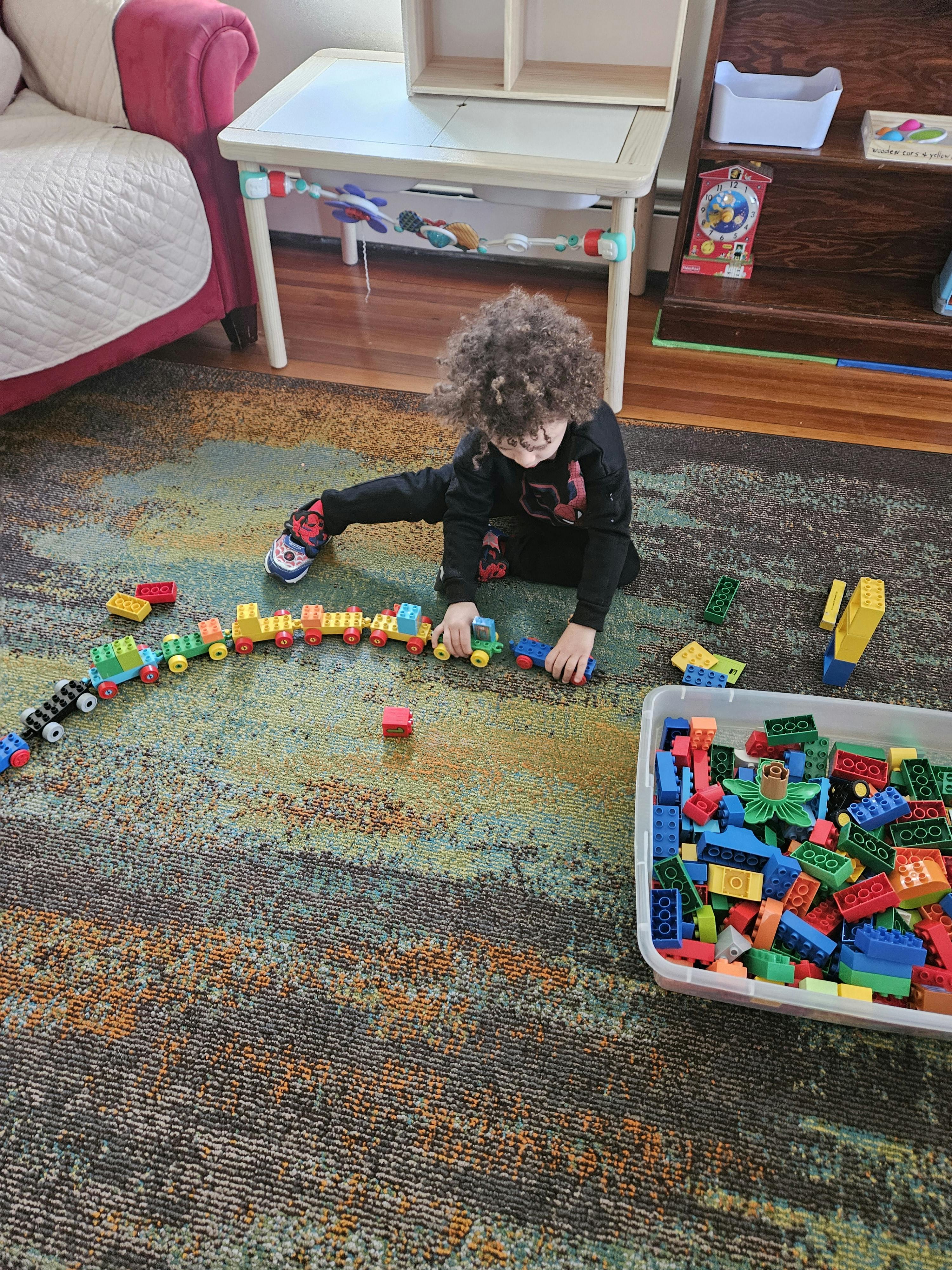 Child playing with a toy train on a carpeted floor