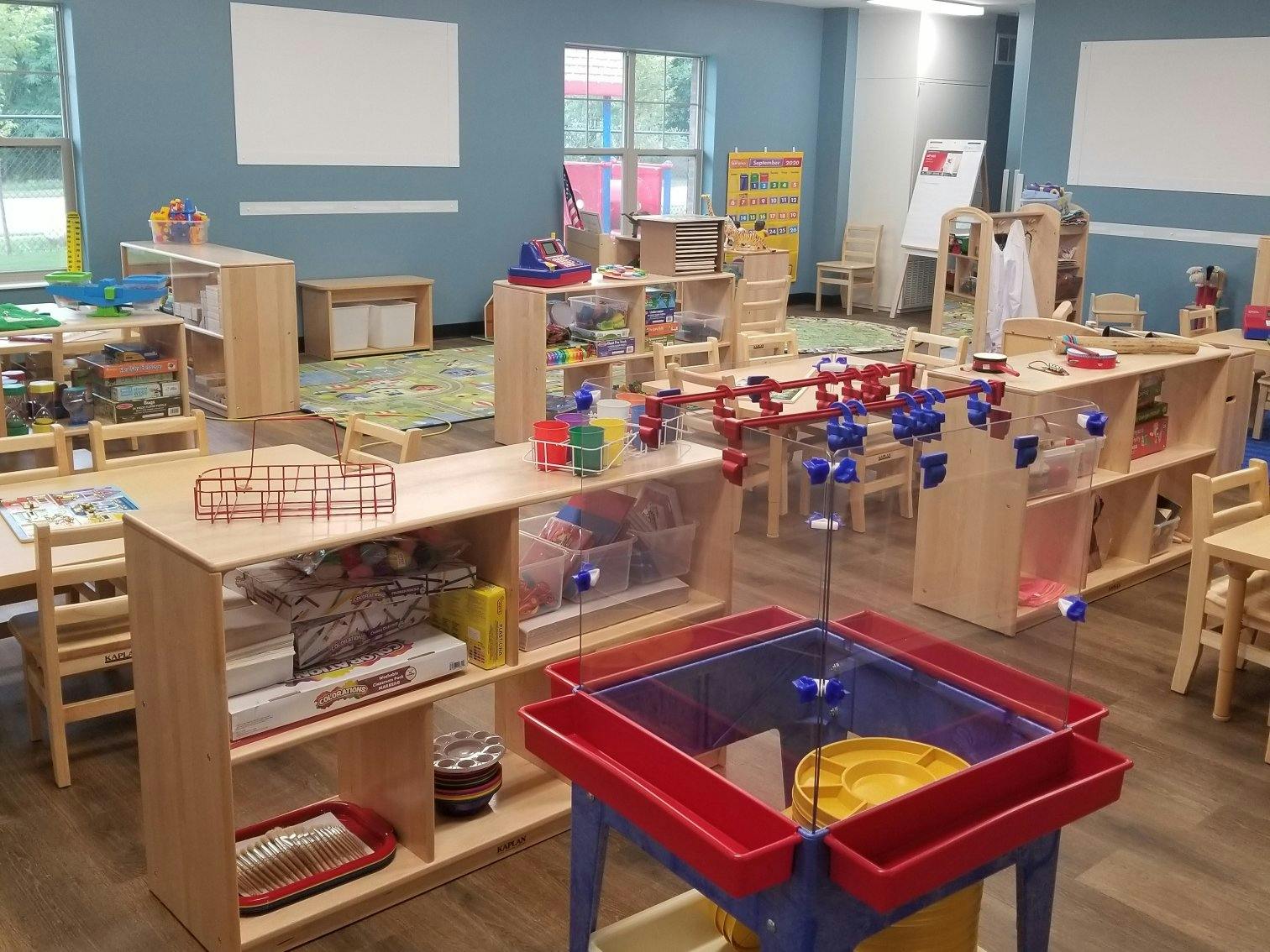 Classroom with play tables, shelves with toys, and foosball table