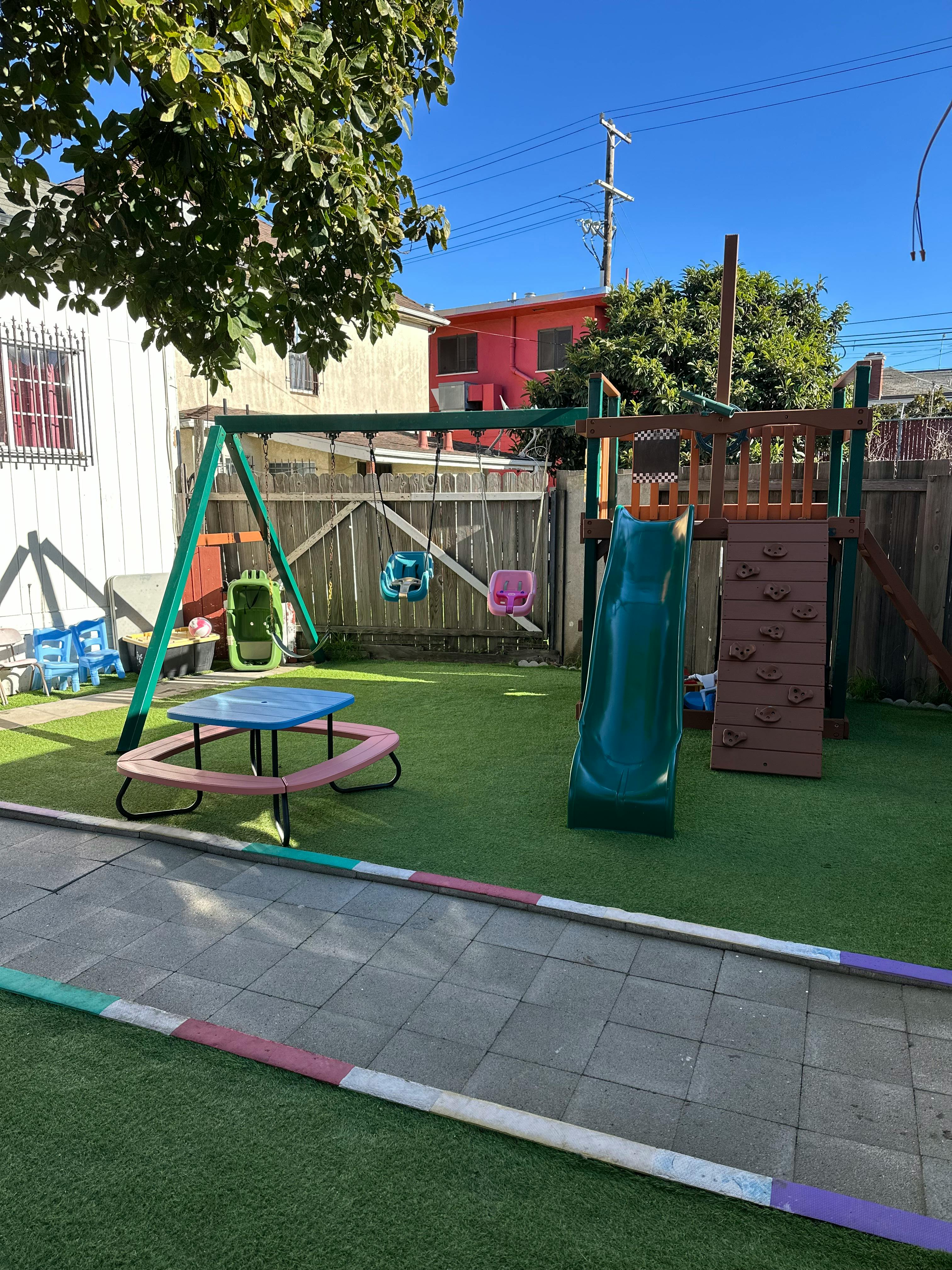 Backyard playground equipment with swings and a slide on synthetic turf